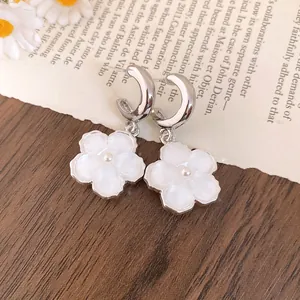 Dettaglio di orecchini a cerchio a C con fiori in resina bianca e perline pendenti