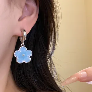 Primo piano dettagliato di un delicato orecchino a fiore in resina blu con perla centrale