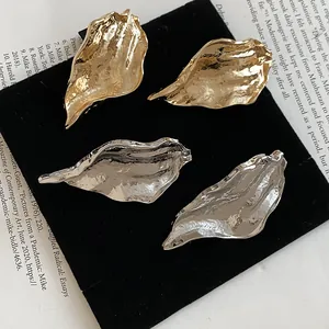 Close-up of irregular 3D leaf metal earrings in gold and silver finishes
