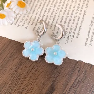 Dettaglio orecchini a fiore in resina azzurra con perle e cerchi a C in argento