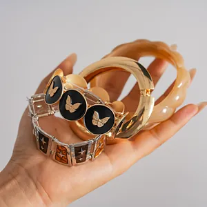 Nahaufnahme eines Retro-Schmetterling-Armbands und eines übergroßen goldenen Armreif-Sets