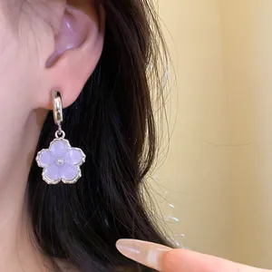 Primo piano di un orecchino a C in argento con fiore in resina lilla e perla