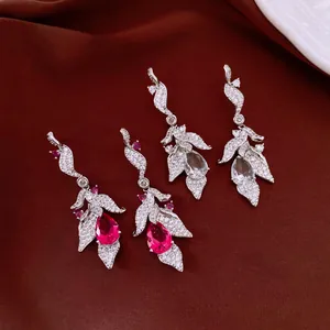 Detailed view of elegant leaf-shaped earrings with pink and clear teardrop zircons.