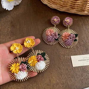 Close-up detail of handmade cloth flower drop earrings with gold sunburst metal design