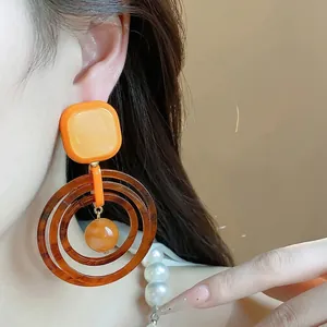 Vintage resin geometric earrings in Maillard brown and orange colors, shown on a female model.