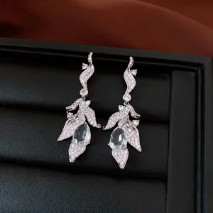 Detailed view of elegant silver leaf earrings featuring sparkling water-drop zircon stones