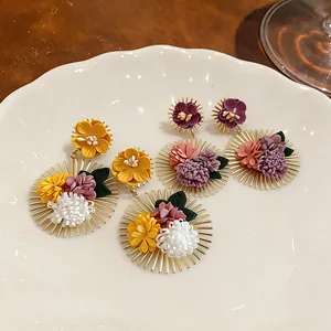 Detailed view of artisanal fabric flower earrings featuring radiant gold-tone metal spikes.