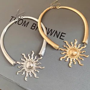 Vintage gold and silver metal sun pendant collar necklace on gray background