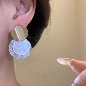 Detailed macro shot of a silver stud earring featuring layered shell-style circular discs
