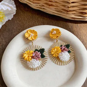 Detail of handcrafted fabric flower earrings with golden radiant sunburst frame.