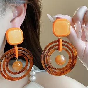 Detailed view of large retro geometric resin earrings in warm Maillard orange tones