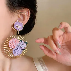 Detailed macro view of elegant oversized Korean fabric floral earrings worn by a model.