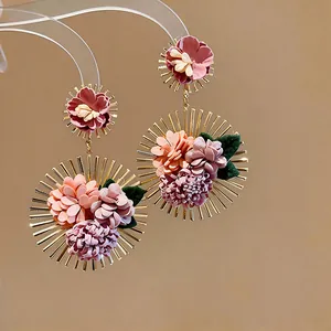 Detailed view of oversized Korean-style fabric flower earrings with gold sunburst frame