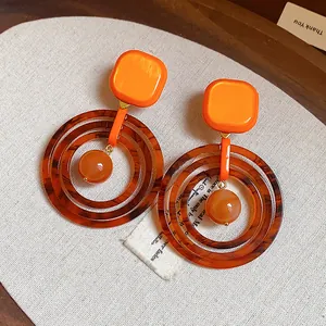 Detailed macro view of vintage orange resin earrings with tortoiseshell hoops
