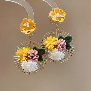 Close-up of vibrant handmade fabric floral drop earrings with golden sunburst frame