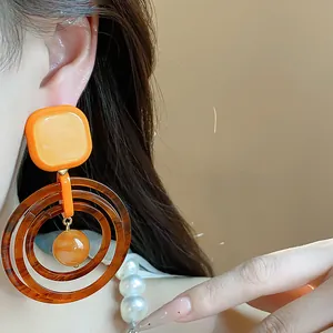 Detailed view showing vintage resin geometric earrings in warm Maillard orange tones.