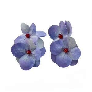 Elegant purple hydrangea flower earrings with red bead center on white background.