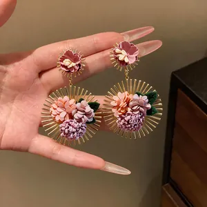 Detail of handmade fabric flower earrings with gold sunburst spikes for holiday look