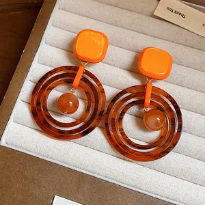 Detail view of retro geometric resin earrings with orange squares and tortoise rings