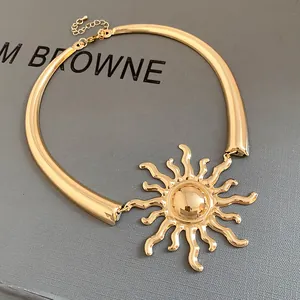 Close-up detail of a vintage gold-toned sun pendant necklace on a grey textured surface.