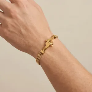 Macrodetail van een gouden roestvrijstalen geweven armband met spijkervormige plaat