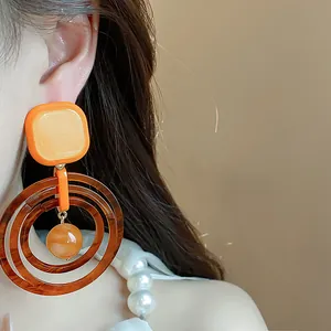 Close-up of vintage geometric resin earrings in orange and brown Maillard tones