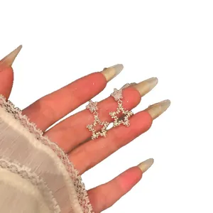 Elegant silver star dangle earrings with sparkling zircon accents shown on hand