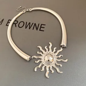 Close-up detail of a silver metal sunburst pendant on a chunky choker necklace
