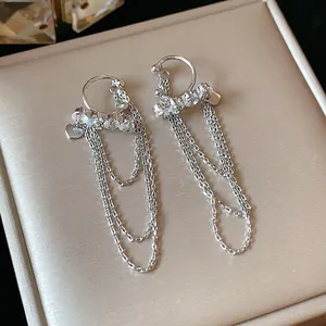 Detail view of silver tassel clip-on earrings featuring zircon stones and heart charms