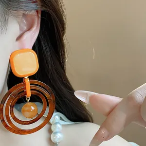 Close-up of vintage resin geometric dangle earrings in warm orange and brown tones