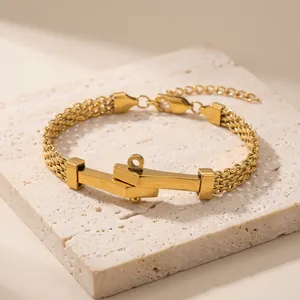 Detailopname van gouden roestvrijstalen gevlochten armband met geometrische sluiting