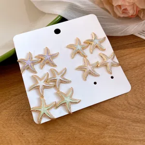 Detail view of a colorful enamel starfish earring set displayed on a white display card