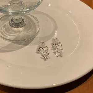 Detailed close-up view of sparkling silver star clip-on earrings on a white ceramic plate