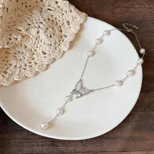 Close-up detail of elegant white butterfly pendant and pearls on gold plated chain