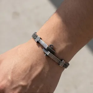Detail van een herenarmband van gevlochten roestvrij staal met spijkerplaat
