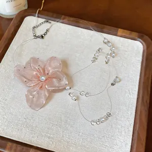 Primer plano de un collar de flores de gasa rosa con detalles de perlas y cuentas de vidrio