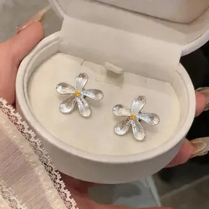 Detailed view of silver flower stud earrings with yellow centers in a jewelry box