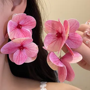 Close-up detail of romantic pink hydrangea flower earrings with red bead center