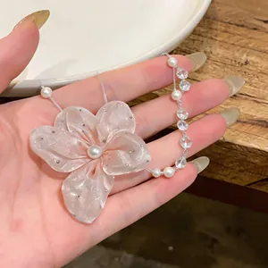 Detalle de un collar elegante con flor de gasa rosa, perlas y cuentas de cristal