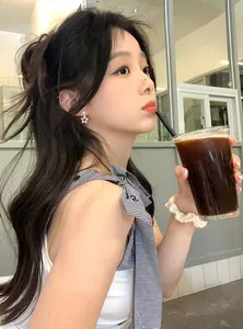 Side view of an Asian woman wearing a sparkling star-shaped zircon earring while drinking coffee
