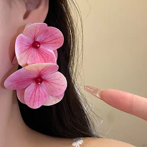 Detailed close-up of large pink hydrangea flower earrings worn for beach vacation style