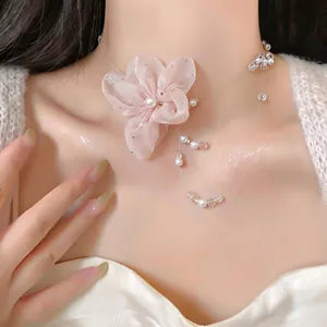 Detalle de primer plano de un collar tipo gargantilla con flor de gasa rosa y perlas francesas