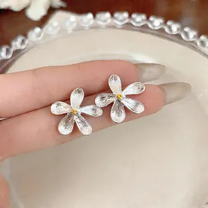 Close-up of elegant silver flower stud earrings with golden stamens.