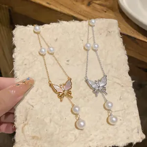 Elegant detail of gold and silver butterfly necklaces featuring zircon and pearls