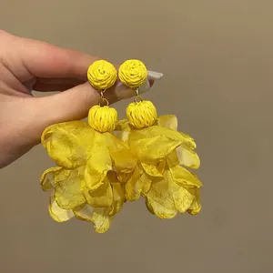 Close-up detail of yellow bohemian chiffon flower petal earrings with woven texture.