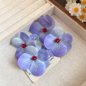 Close-up of purple hydrangea flower earrings with red bead centers in a jewelry box