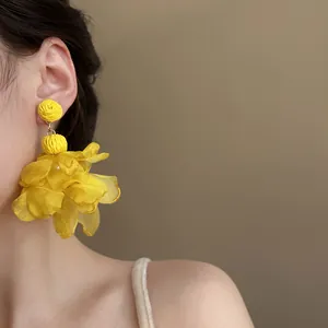 Close-up of oversized vibrant yellow chiffon petal earrings worn by a female Asian model