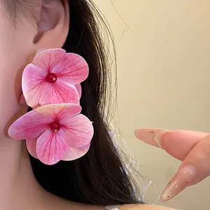 Close-up of pink fabric flower earrings with red bead center on model's ear