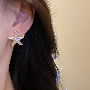 Close-up detail of a starfish ear stud featuring purple enamel and a gold-tone border