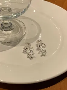 Close-up of sweet star-shaped silver earrings with sparkling zircon on a white plate